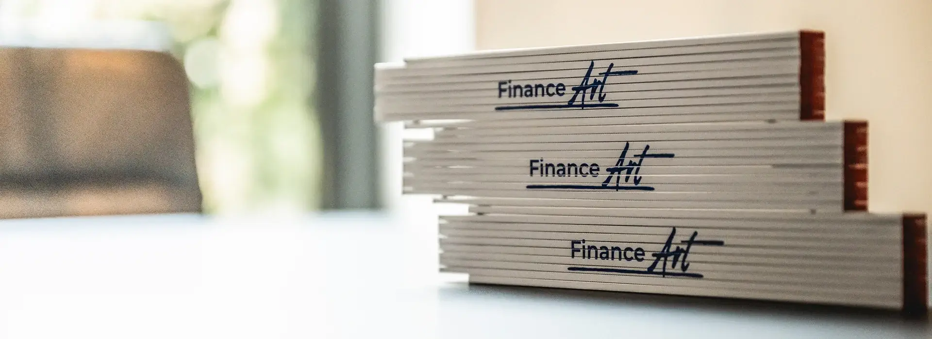 Zollstöcke mit FinanceArt-Logo – symbolisch für Finanzierungsplanung und Vergleich